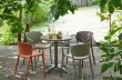 Gedeckter Tisch mit farbigen Stühlen im Garten