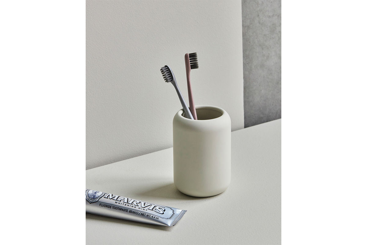 Zahnputzbecher mit 2 Zahnbürsten und Zahnpasta dekoriert